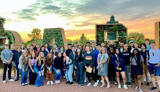 Large grouo of students standing in front of a sunset