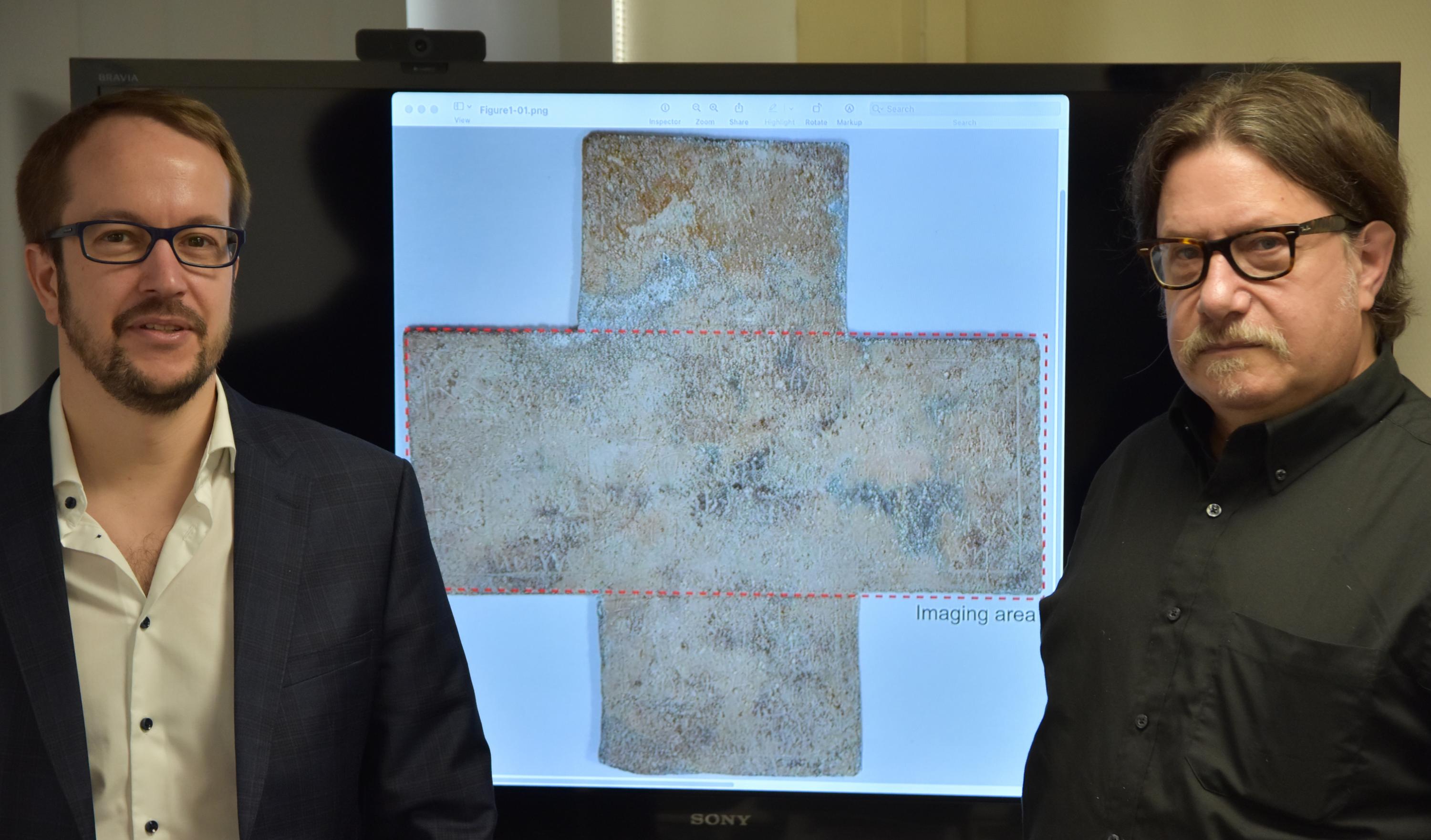 Georgia Tech professor David Citrin (right) and adjunct professor Alexandre Locquet stand in front of an image of the 16th-century funerary cross used in their study. Credit: Nicolas Jacquet